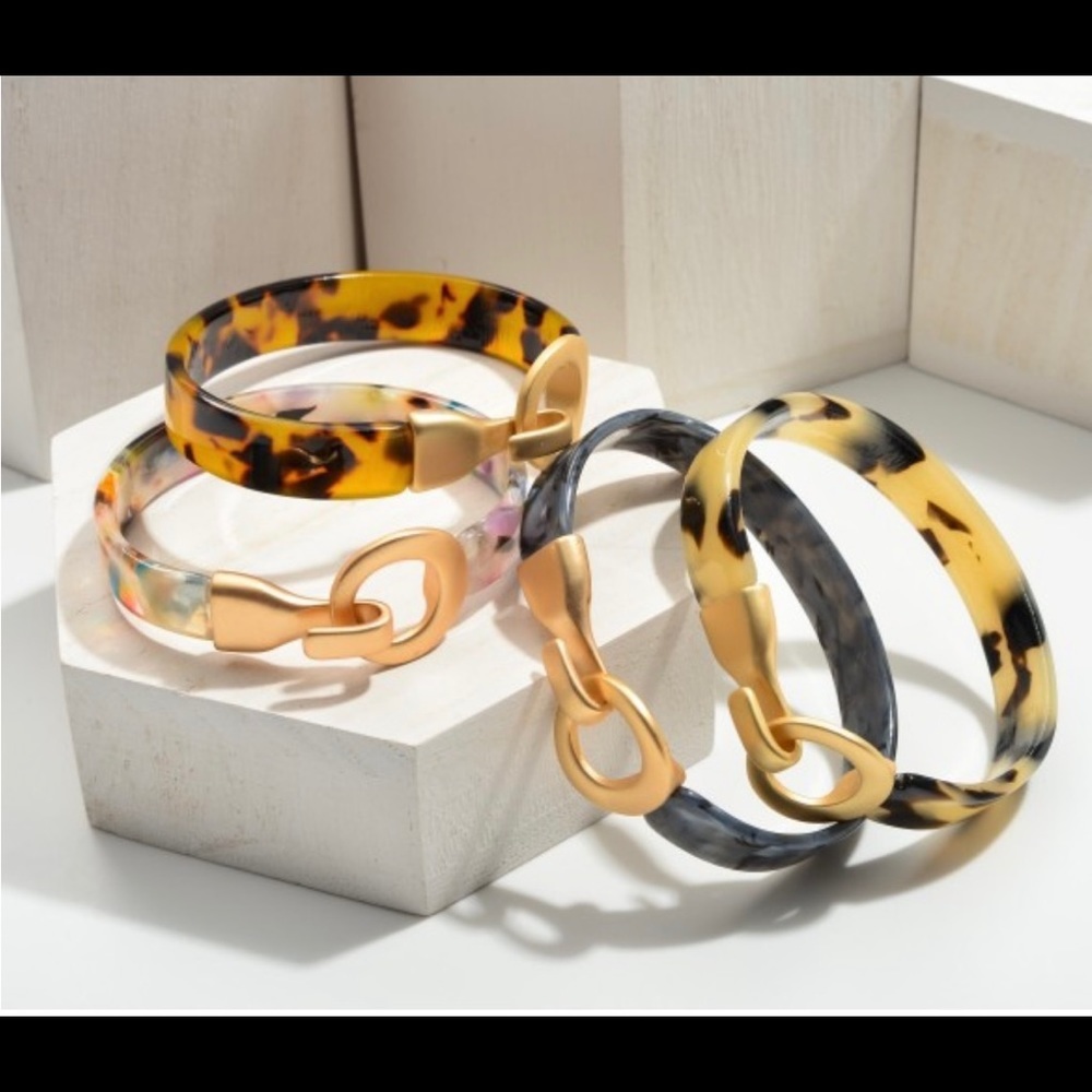 Resin bangle bracelet featuring hook and eye closure.